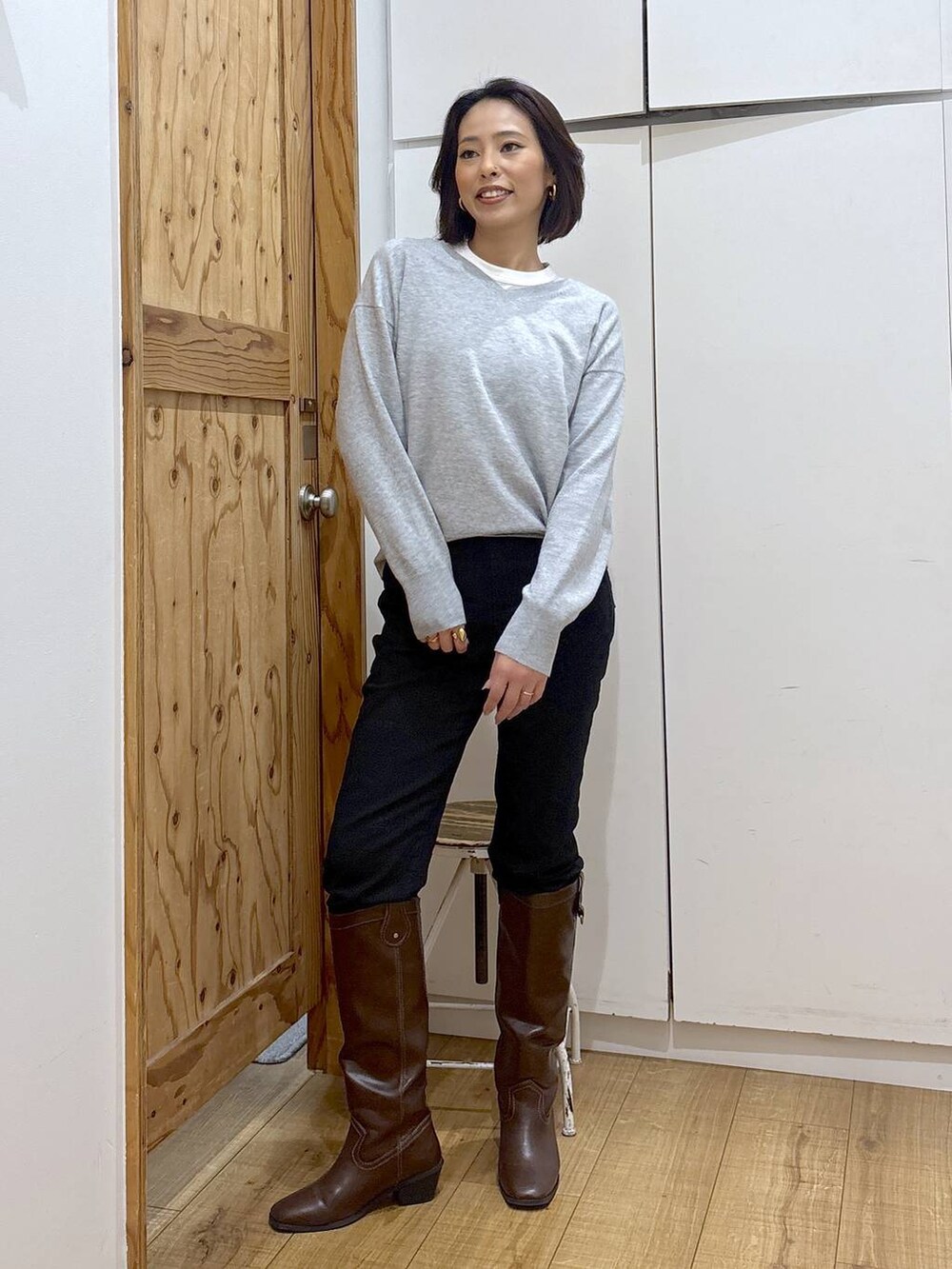 ブラック系のデニムパンツ、ブラウン系のブーツ、グレー系のニット/セーターを着用したレディースの秋コーディネートの2枚目の写真