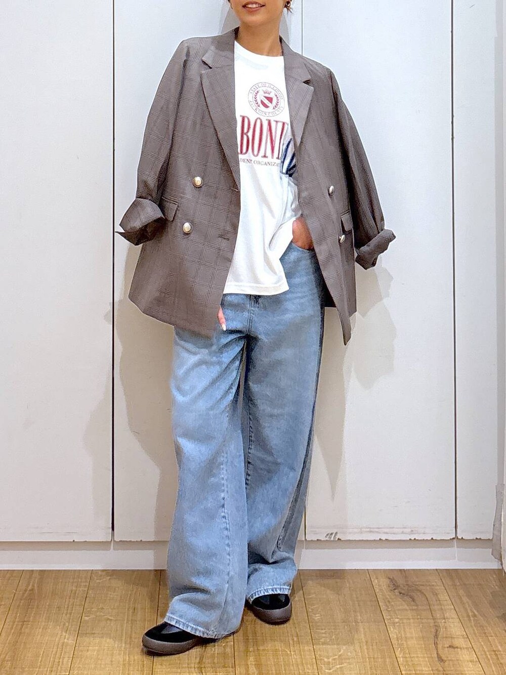 ブラック系のスニーカー、ブラウン系のテーラードジャケット、ブルー系のデニムパンツを着用したレディースの秋コーディネートの5枚目の写真