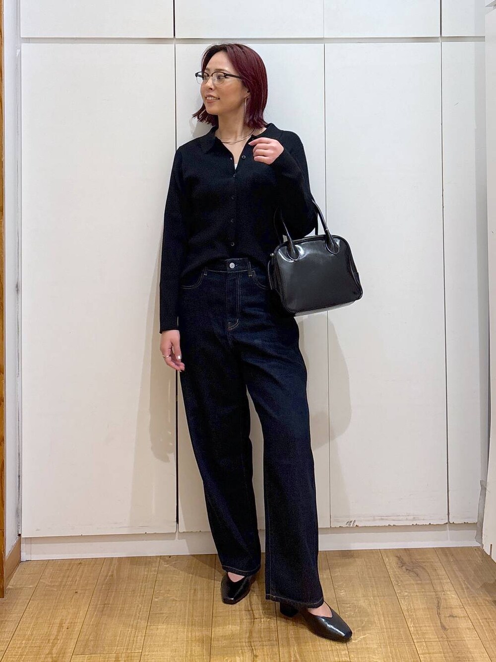 ブルー系のデニムパンツ、ブラック系のボストンバッグ、ブラック系のカーディガン/ボレロを着用したレディースの春コーディネートの2枚目の写真