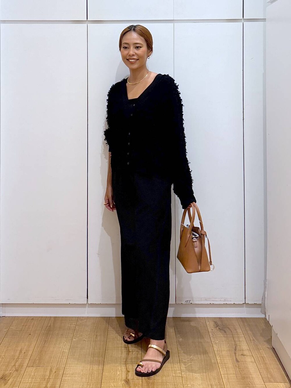 ブラウン系のショルダーバッグ、ブラック系のキャミソール、ブラウン系のサンダルを着用したレディースの秋コーディネートの3枚目の写真