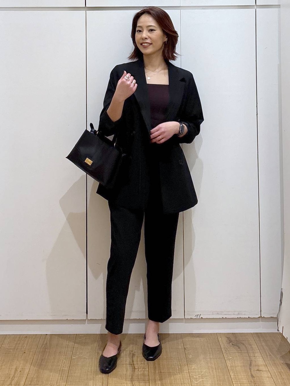 ブラック系のパンプス、ブラック系のスラックス、ブラック系のテーラードジャケットを着用したレディースの春コーディネートの3枚目の写真