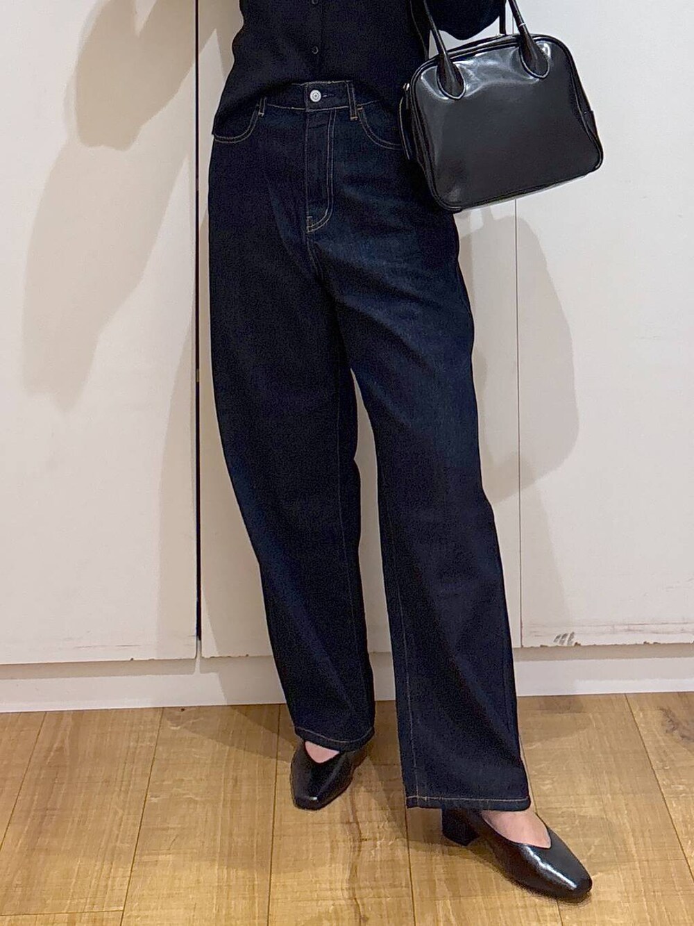 ブルー系のデニムパンツ、ブラック系のボストンバッグ、ブラック系のカーディガン/ボレロを着用したレディースの春コーディネートの8枚目の写真