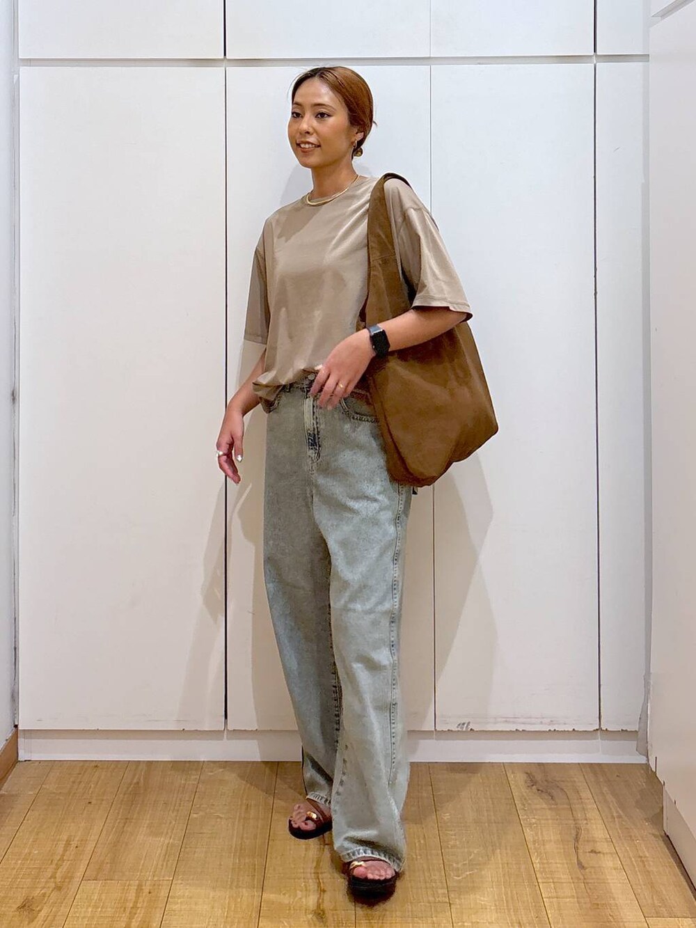 ブラウン系のサンダル、ベージュ系のTシャツ/カットソー、ブルー系のデニムパンツを着用したレディースの秋コーディネートの3枚目の写真