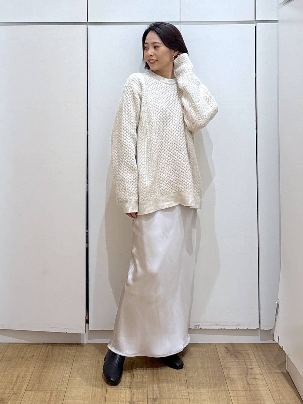 ホワイト系のニット/セーター、ブラック系のブーツ、グレー系のスカートを着用したレディースの冬コーディネートの2枚目の写真