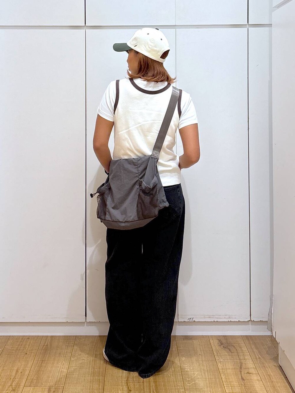 グレー系のトートバッグ、ブラック系のデニムパンツ、ホワイト系のタンクトップを着用したレディースの夏コーディネートの5枚目の写真