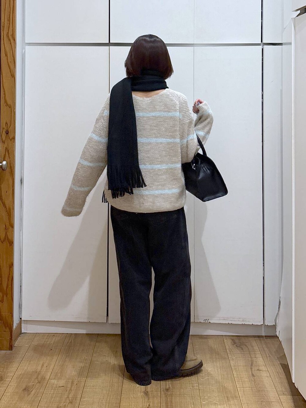 ブラック系のデニムパンツ、ベージュ系のローファー、ブラック系のショルダーバッグを着用したレディースの冬コーディネートの3枚目の写真