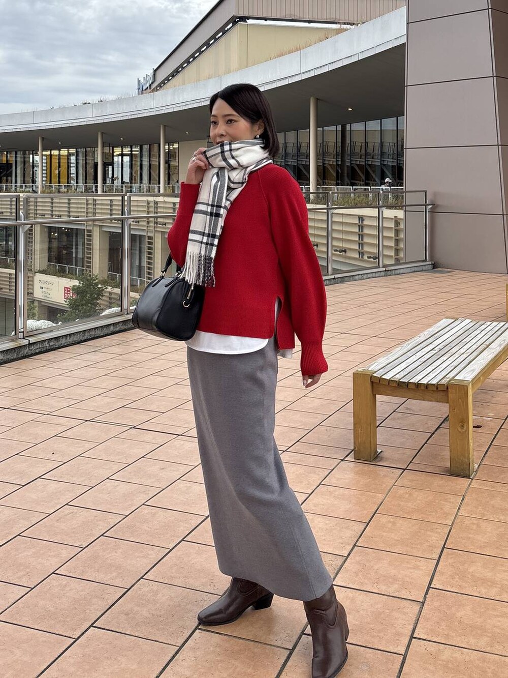 ブラウン系のチェスターコート、グレー系のスカート、ホワイト系のTシャツ/カットソーを着用したレディースの秋コーディネートの5枚目の写真