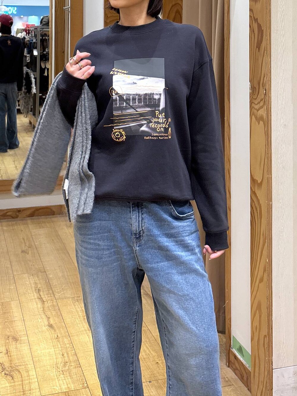 グレー系のスウェット、ブルー系のデニムパンツ、レッド系のハットを着用したレディースの秋コーディネートの5枚目の写真