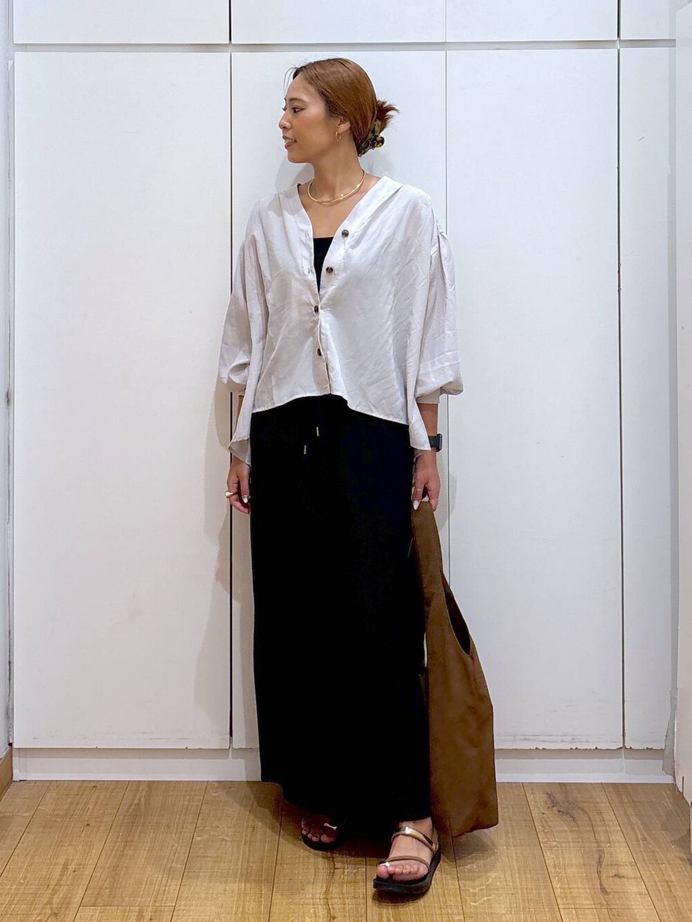 ブラック系のキャミソール、ブラウン系のサンダル、ブラック系のスカートを着用したレディースの秋コーディネートの3枚目の写真