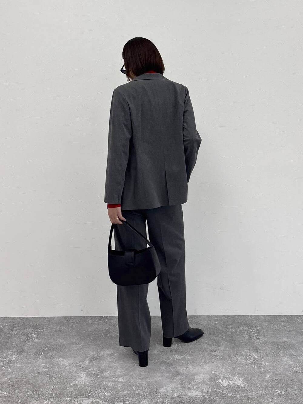 グレー系のスラックス、グレー系のテーラードジャケット、ブラック系のブーツを着用したレディースの冬コーディネートの7枚目の写真