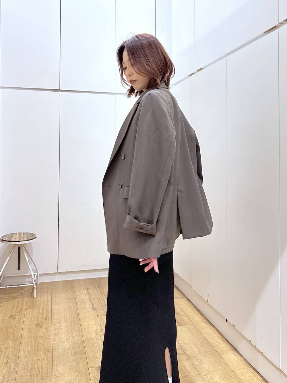 ブラウン系のテーラードジャケット、ブラック系のスカート、ゴールド系のネックレスを着用したレディースの春コーディネートの6枚目の写真