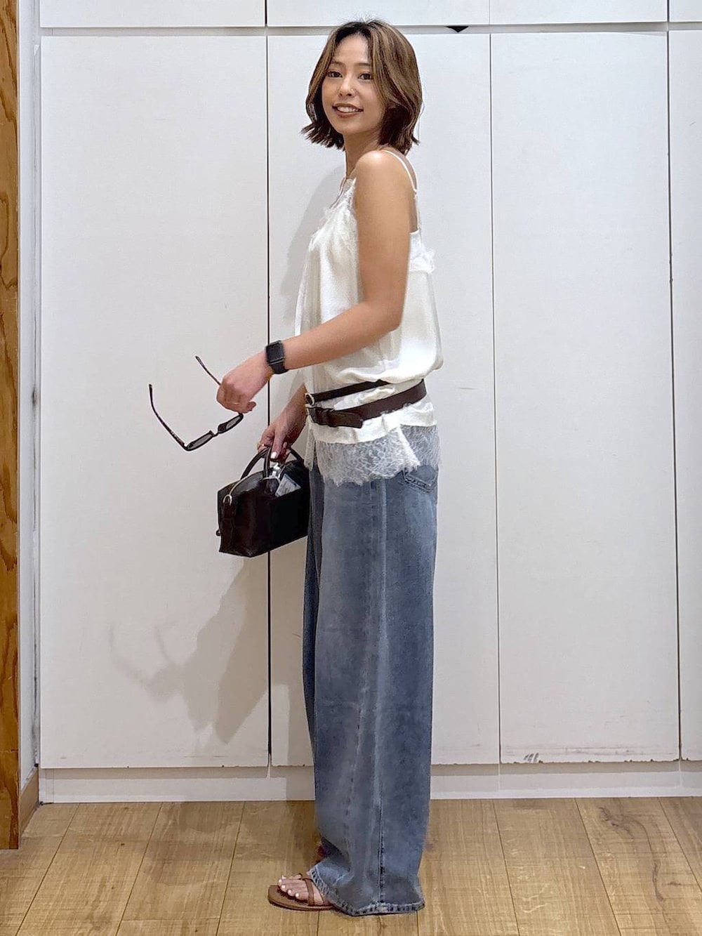 ホワイト系のキャミソール、ブルー系のデニムパンツ、ホワイト系のキャミソールを着用したレディースの春コーディネートの4枚目の写真