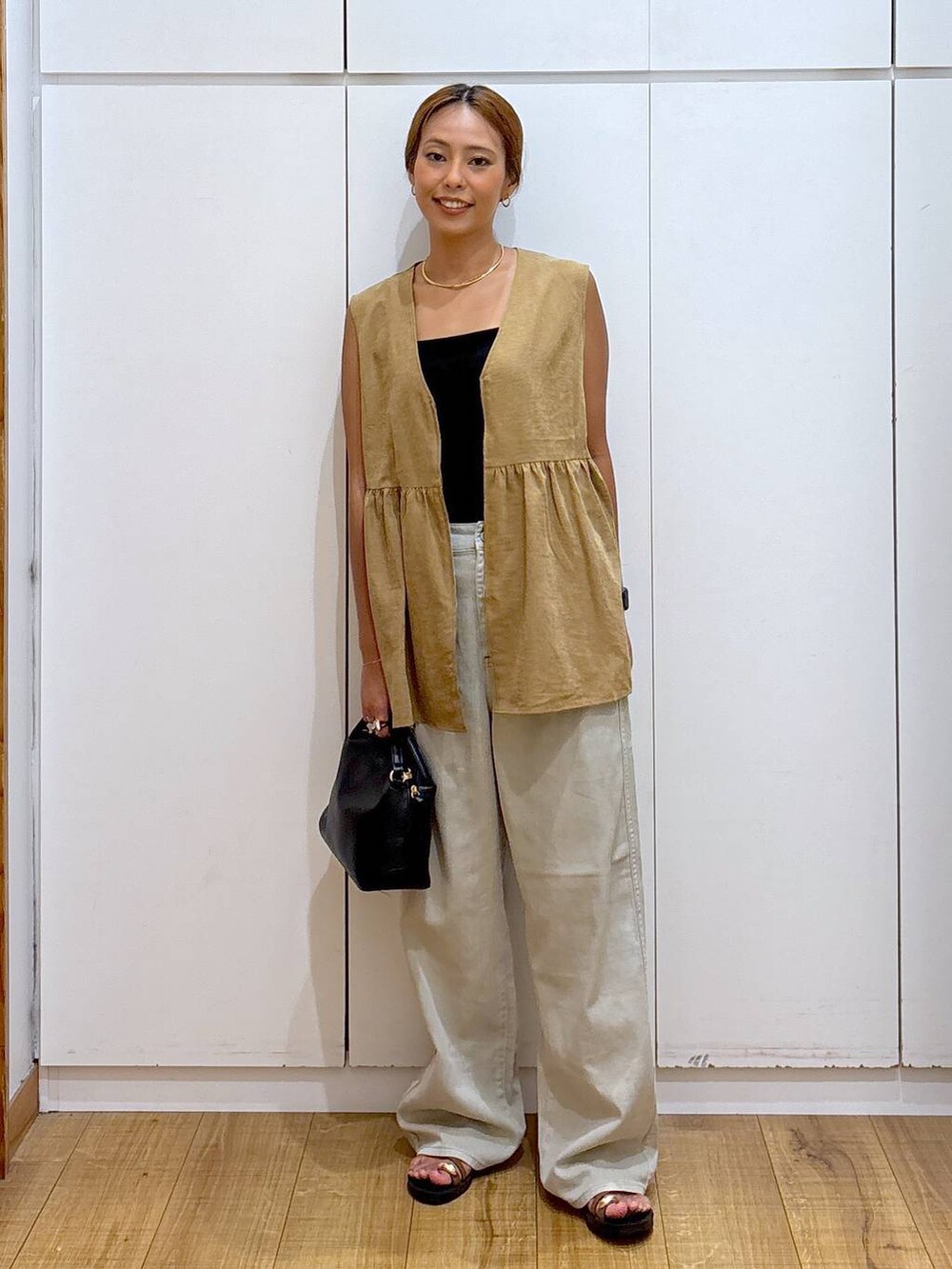 ブラック系のショルダーバッグ、ブラック系のキャミソール、ブラウン系のサンダルを着用したレディースの秋コーディネートの3枚目の写真