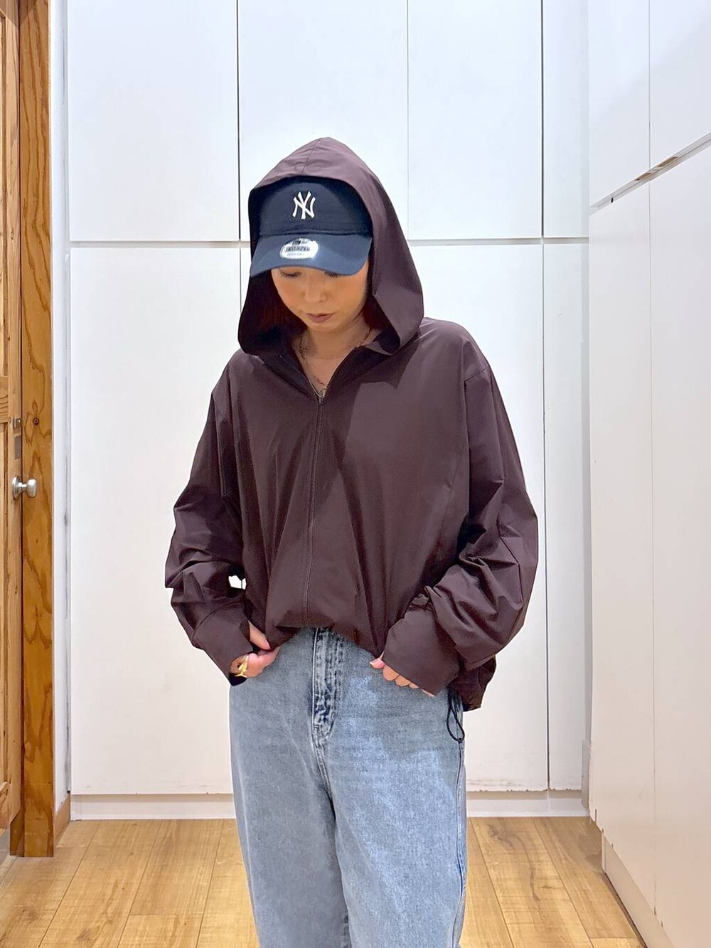 ブルー系のデニムパンツ、ブラウン系のマウンテンパーカー、ブルー系のキャップを着用したレディースの夏コーディネートの4枚目の写真