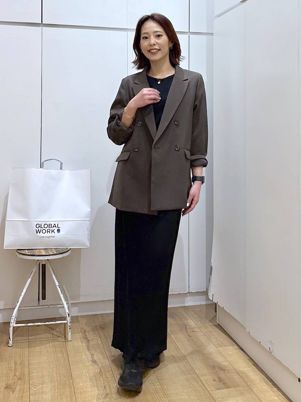 ブラウン系のテーラードジャケット、ブラック系のスカート、ゴールド系のネックレスを着用したレディースの春コーディネートの3枚目の写真