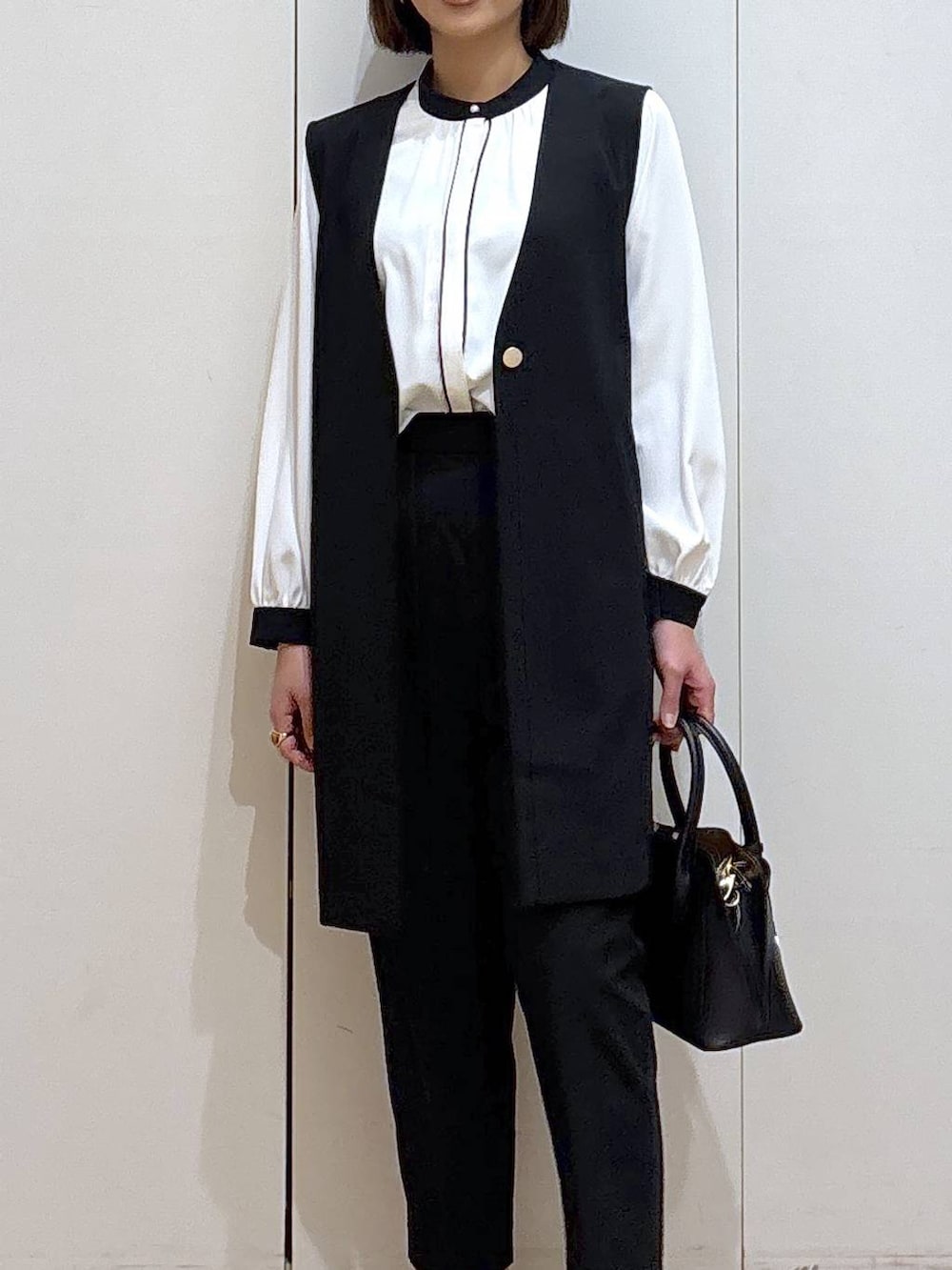 ブラック系のショルダーバッグ、ブラック系のパンプス、ブラック系のスラックスを着用したレディースの冬コーディネートの5枚目の写真