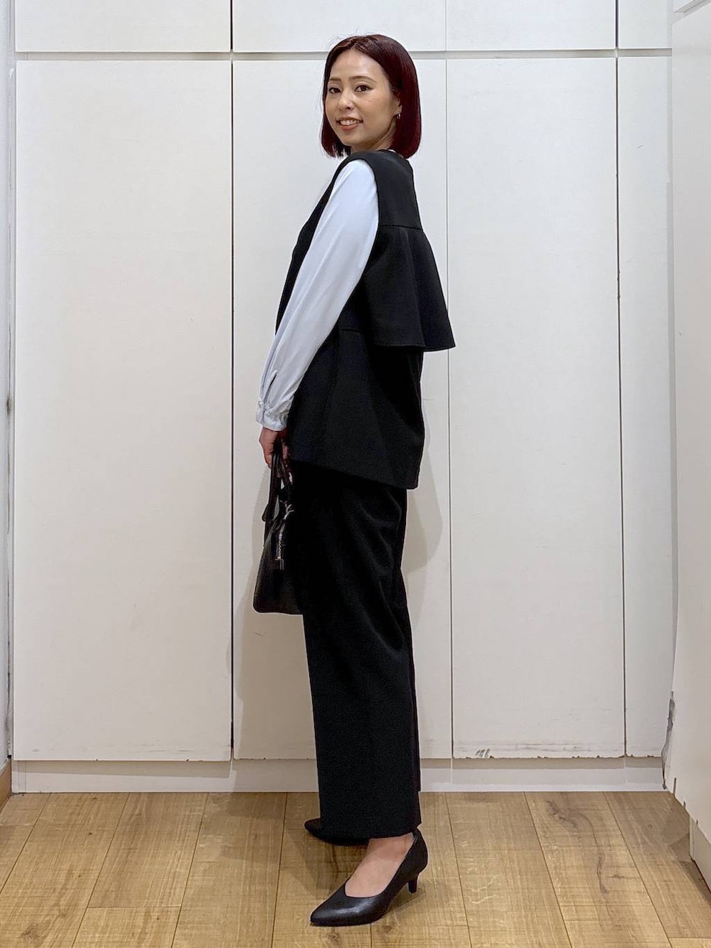 ブラック系のショルダーバッグ、ブラック系のパンプス、ブルー系のシャツ/ブラウスを着用したレディースの春コーディネートの5枚目の写真