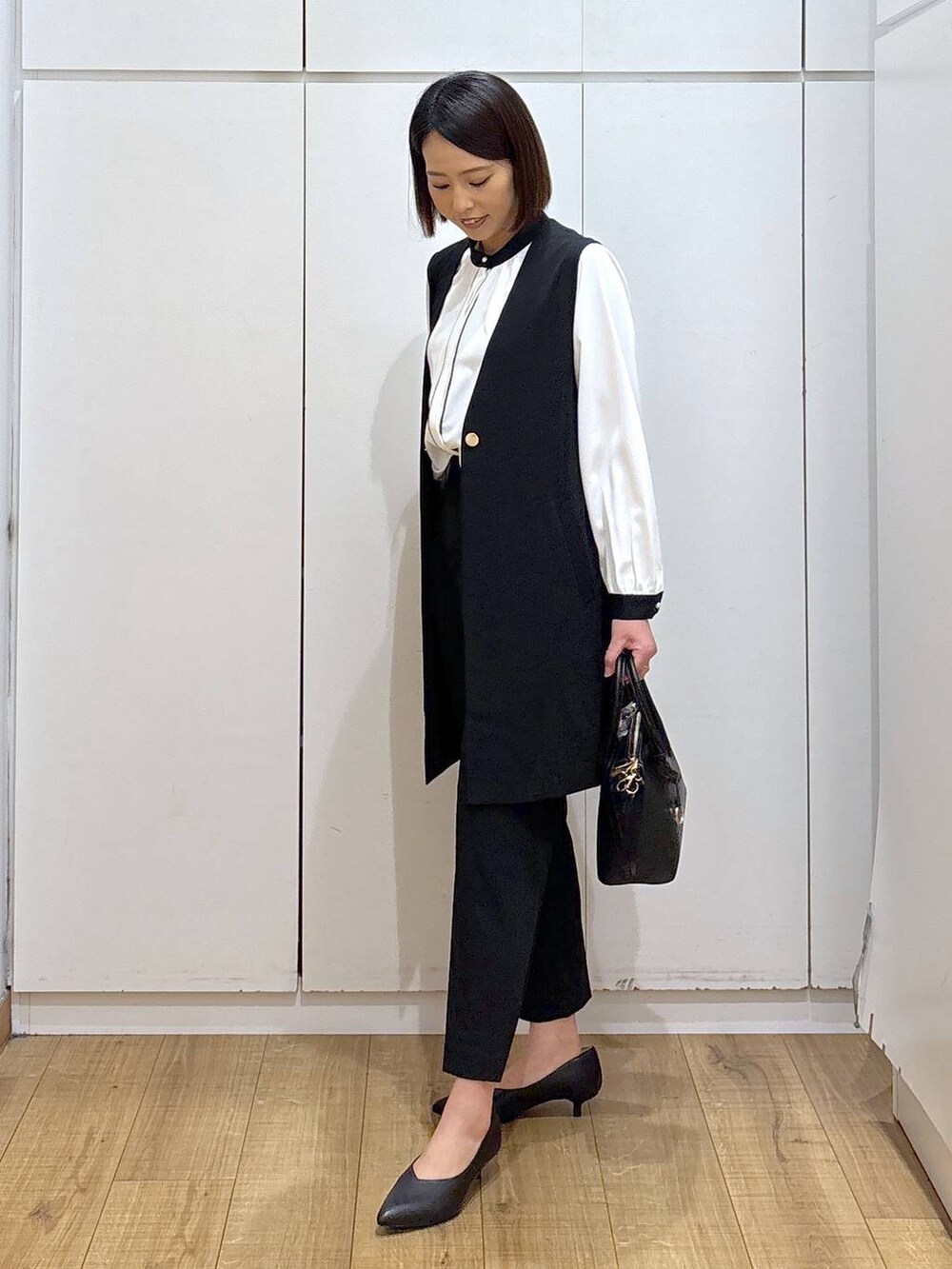 ブラック系のショルダーバッグ、ブラック系のパンプス、ブラック系のスラックスを着用したレディースの冬コーディネートの6枚目の写真