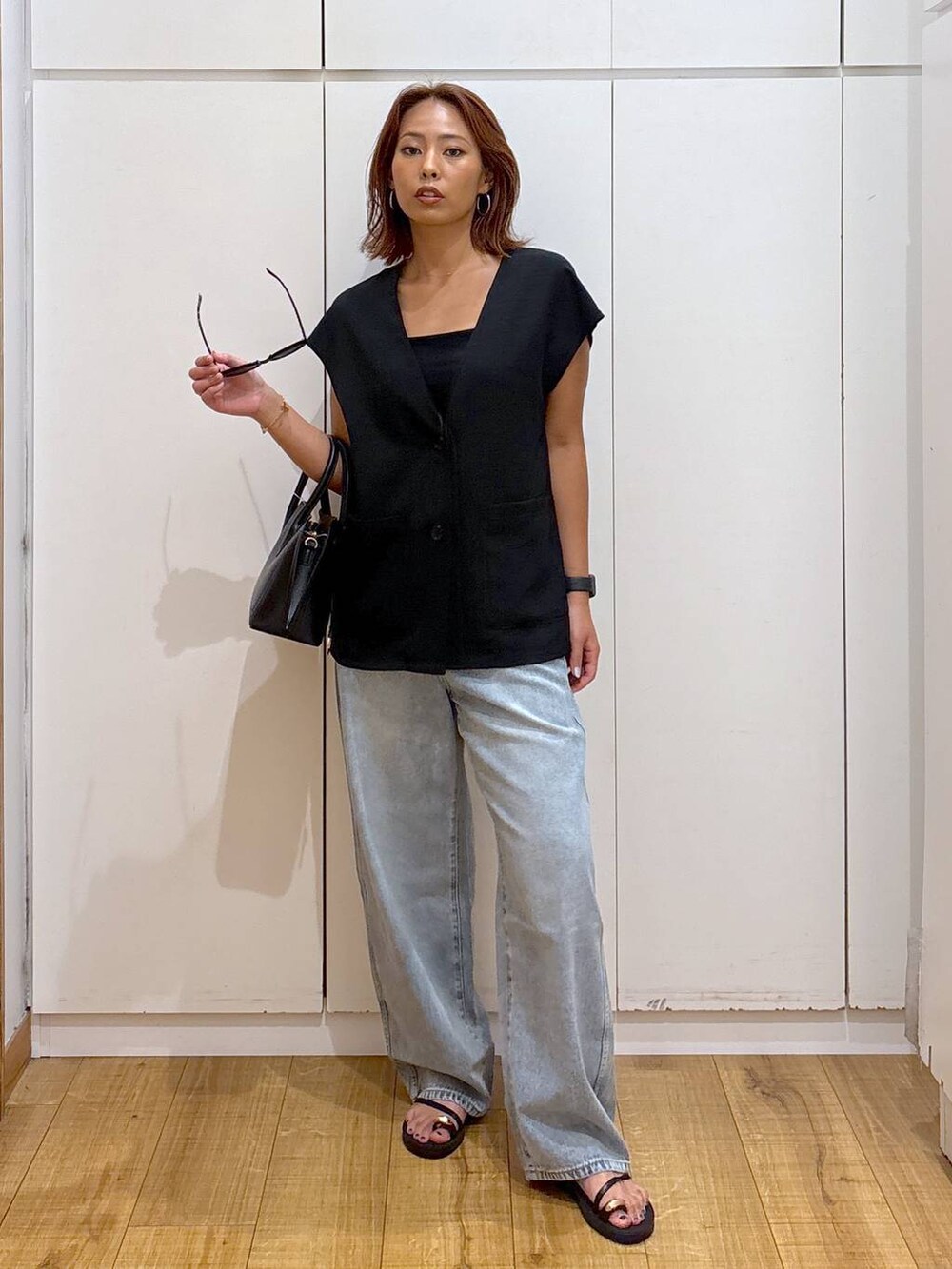 ブルー系のデニムパンツ、ブラック系のショルダーバッグ、ブラック系のキャミソールを着用したレディースの夏コーディネートの2枚目の写真