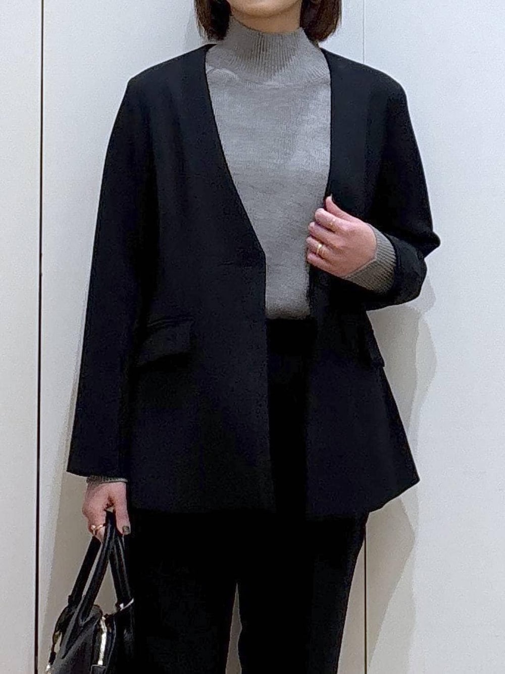 ブラック系のショルダーバッグ、ブラック系のパンプス、グレー系のニット/セーターを着用したレディースの冬コーディネートの3枚目の写真