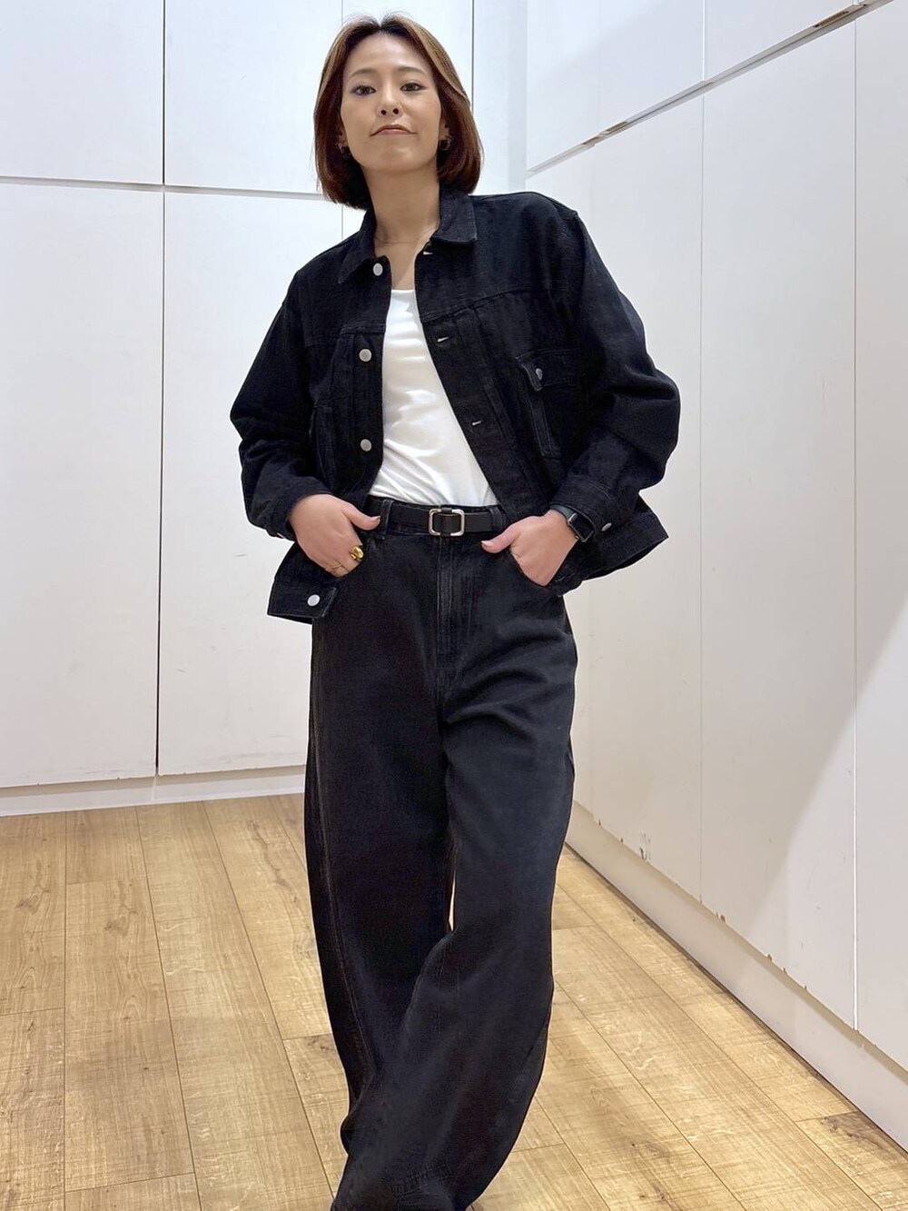 ブラック系のデニムパンツ、ブラック系のデニムジャケット、ホワイト系のキャミソールを着用したレディースの春コーディネートの4枚目の写真