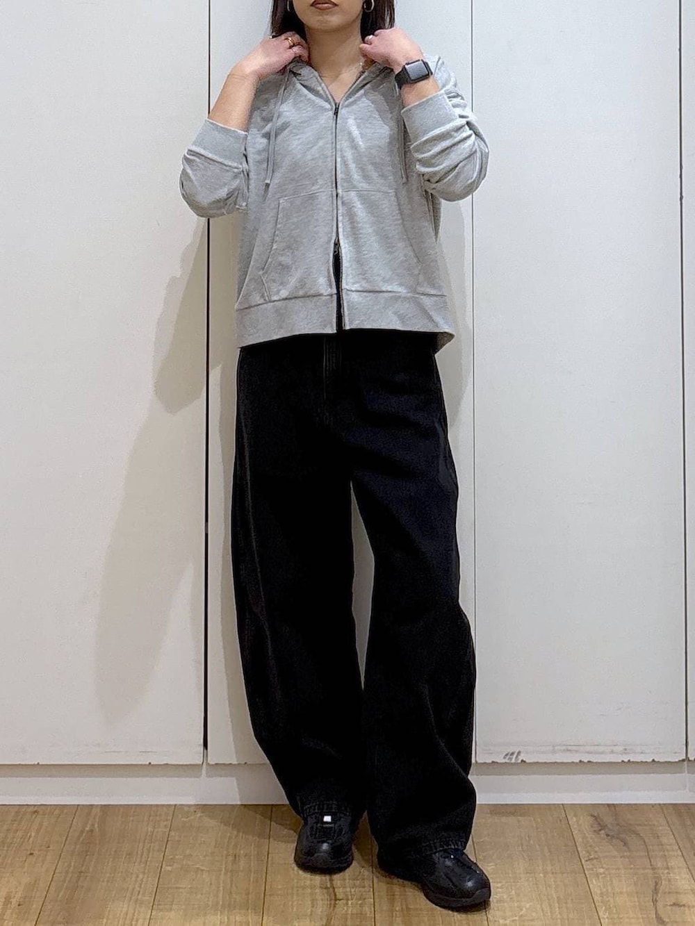 ブラック系のスニーカー、ブラック系のデニムパンツ、グレー系のパーカーを着用したレディースの冬コーディネートの3枚目の写真