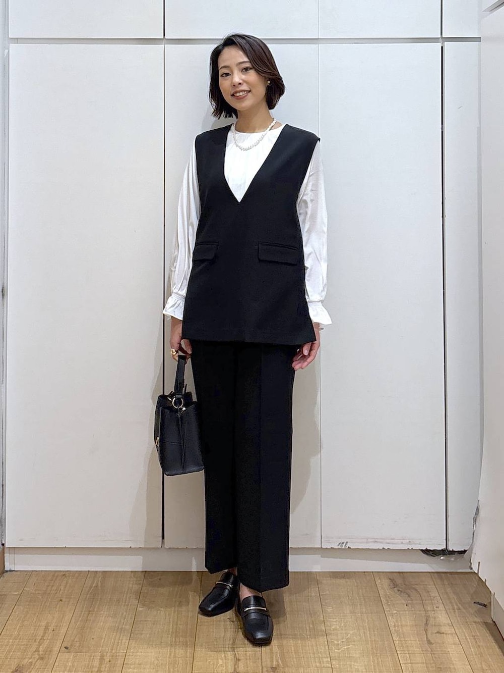 ブラック系のローファー、ブラック系のセットアップ、ブラック系のショルダーバッグを着用したレディースの冬コーディネートの2枚目の写真