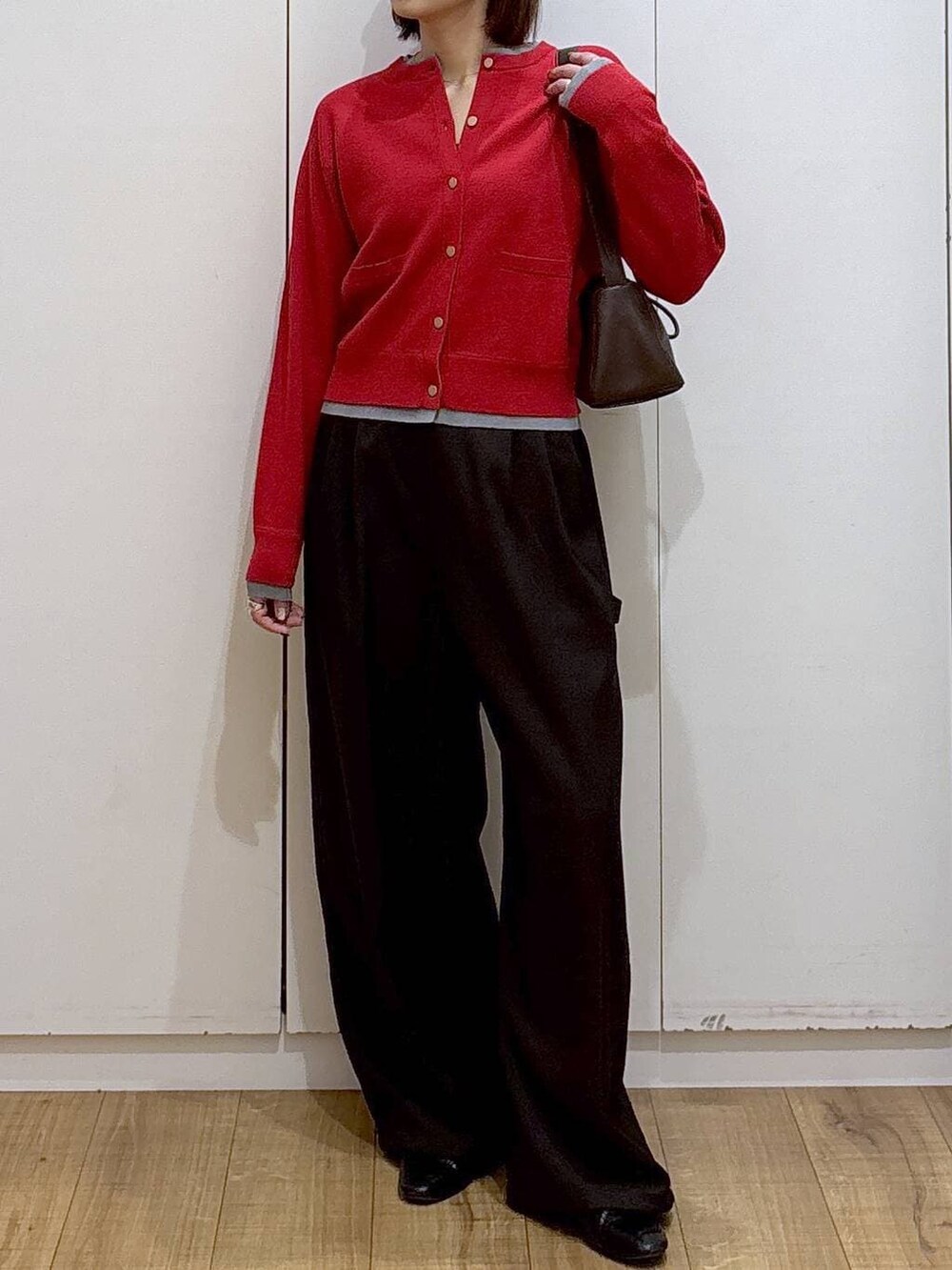 ブラック系のローファー、レッド系のカーディガン/ボレロ、ブラウン系のショルダーバッグを着用したレディースの冬コーディネートの2枚目の写真