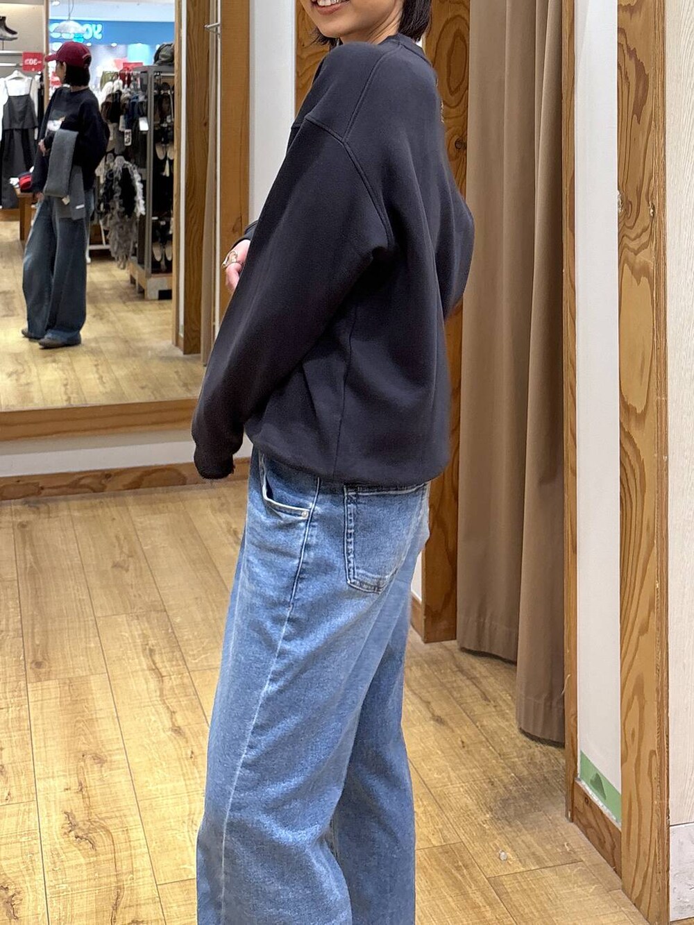 グレー系のスウェット、ブルー系のデニムパンツ、レッド系のハットを着用したレディースの秋コーディネートの6枚目の写真