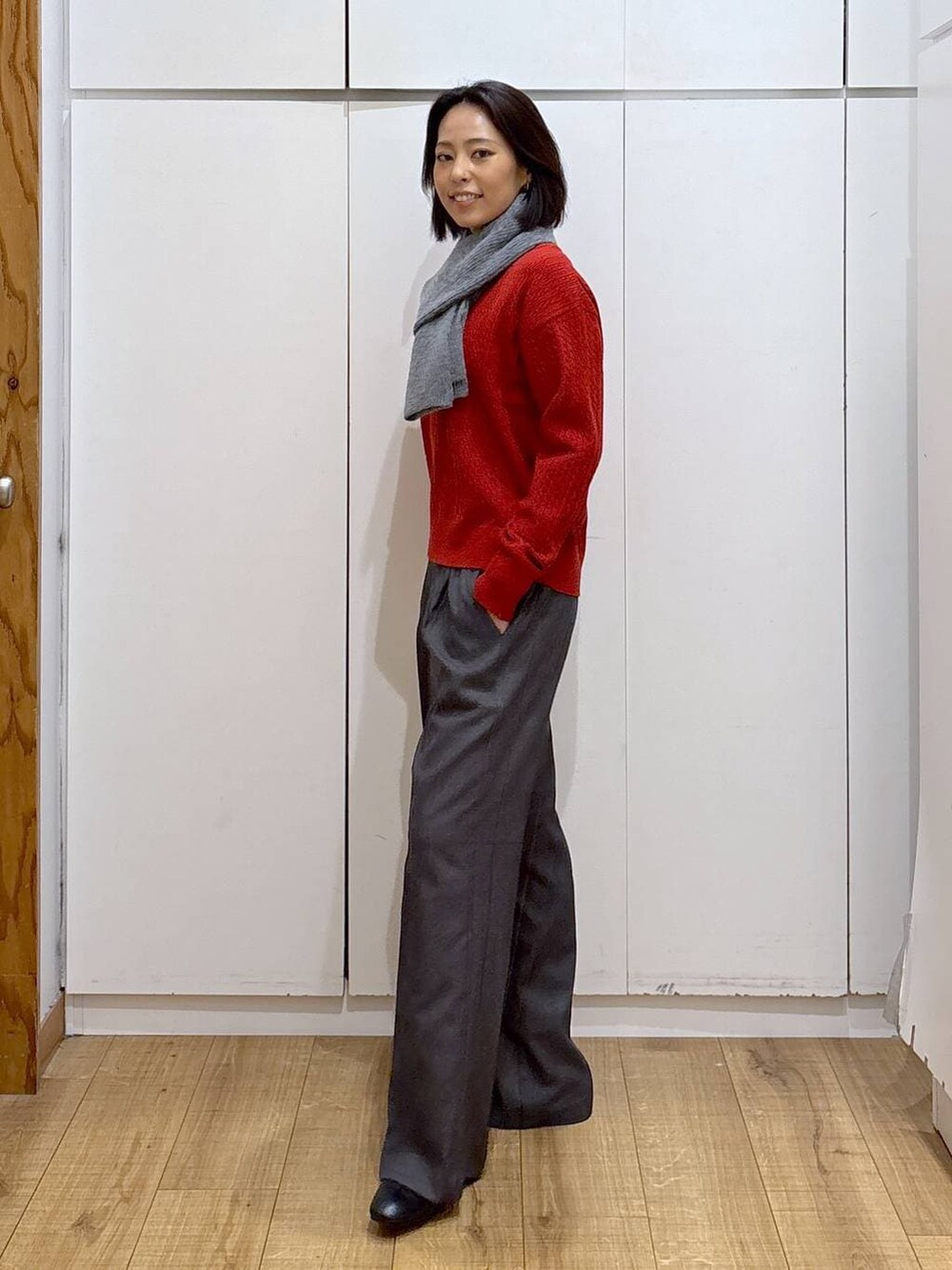 グレー系のその他パンツ、ブラック系のブーツ、レッド系のニット/セーターを着用したレディースの秋コーディネートの2枚目の写真