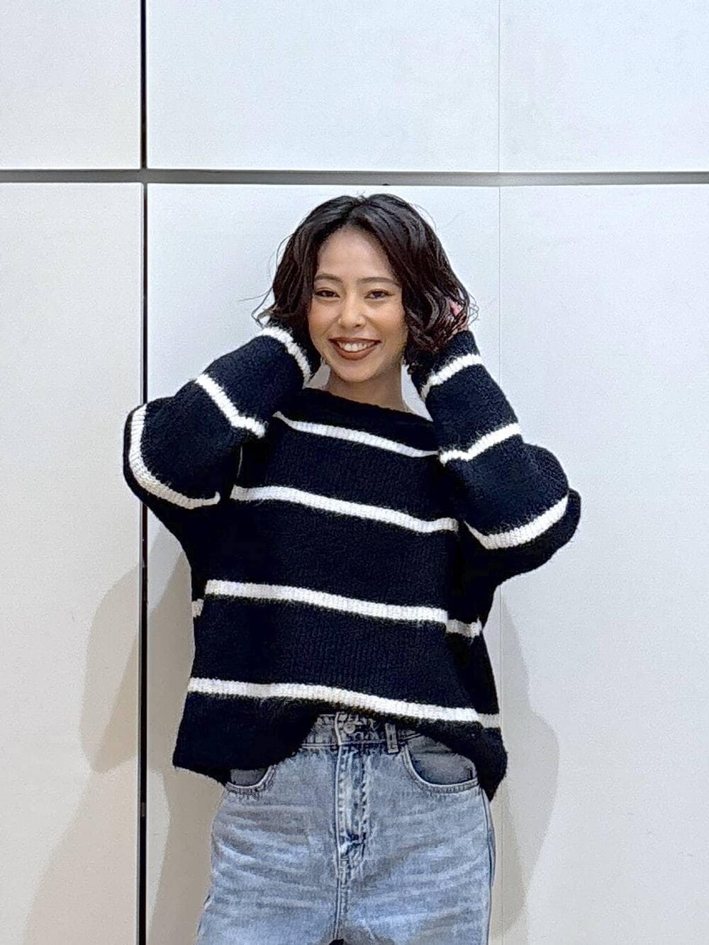 ブルー系のデニムパンツ、ブルー系のニット/セーター、ゴールド系のピアス(両耳用)を着用したレディースの冬コーディネートの4枚目の写真