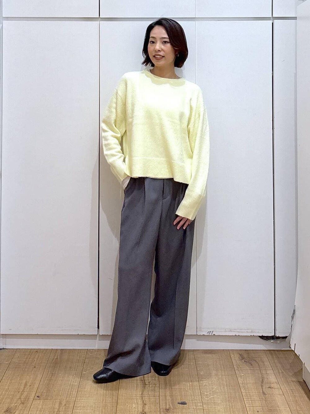 イエロー系のニット/セーター、ブラック系のブーツ、ゴールド系のピアス（両耳用）を着用したレディースの冬コーディネートの3枚目の写真