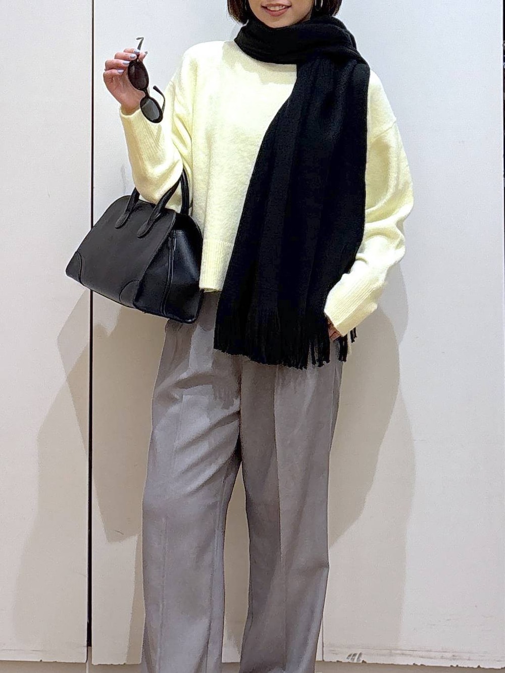 イエロー系のニット/セーター、グレー系のその他パンツ、ブラック系のショルダーバッグを着用したレディースの冬コーディネートの6枚目の写真