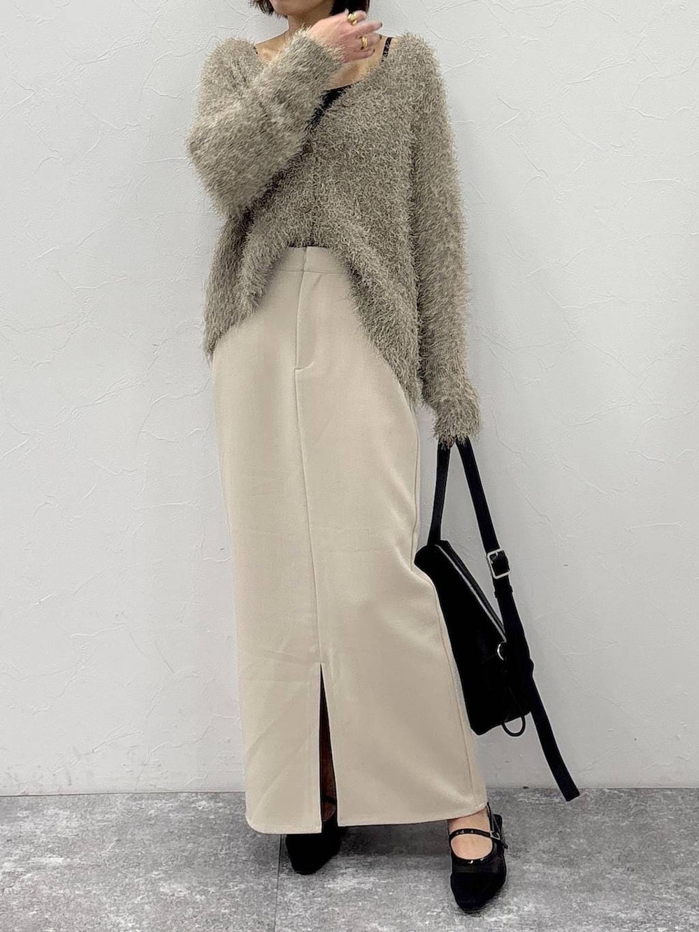 ブラック系のショルダーバッグ、ベージュ系のスカート、ゴールド系のピアス(両耳用)を着用したレディースの冬コーディネートの7枚目の写真