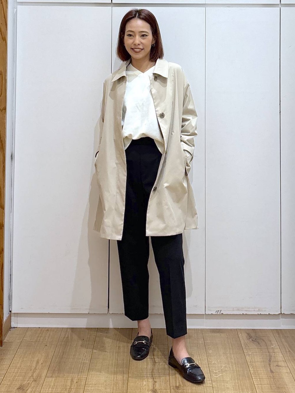 ブラック系のローファー、ブラック系のスラックス、ベージュ系のステンカラーコートを着用したレディースの春コーディネートの3枚目の写真