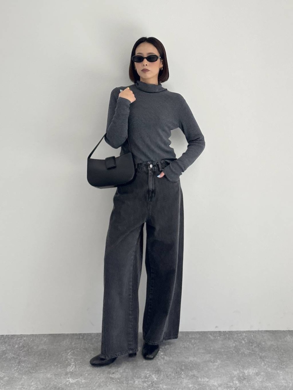 ブラック系のデニムパンツ、ブラック系のブーツ、グレー系のニット/セーターを着用したレディースの秋コーディネートの8枚目の写真