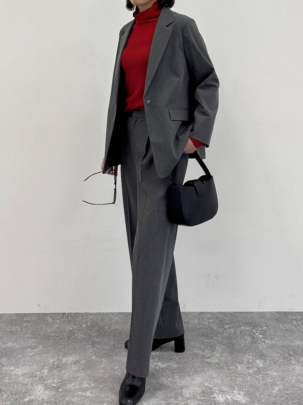 グレー系のスラックス、グレー系のテーラードジャケット、ブラック系のブーツを着用したレディースの冬コーディネートの5枚目の写真