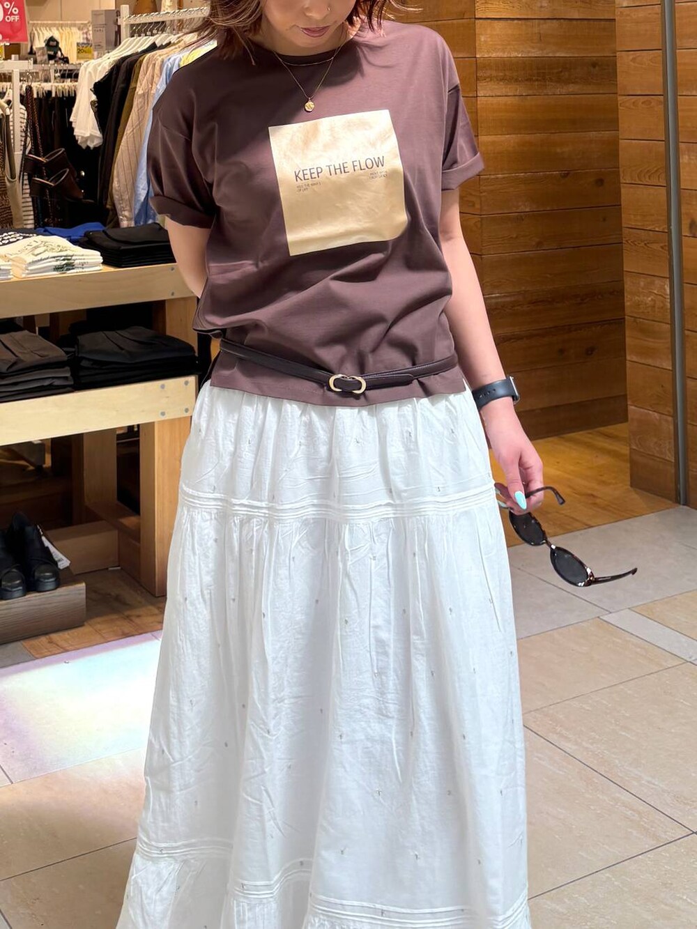 ホワイト系のスカート、ブラウン系のTシャツ/カットソー、ブラック系のサンダルを着用したレディースの春コーディネートの6枚目の写真
