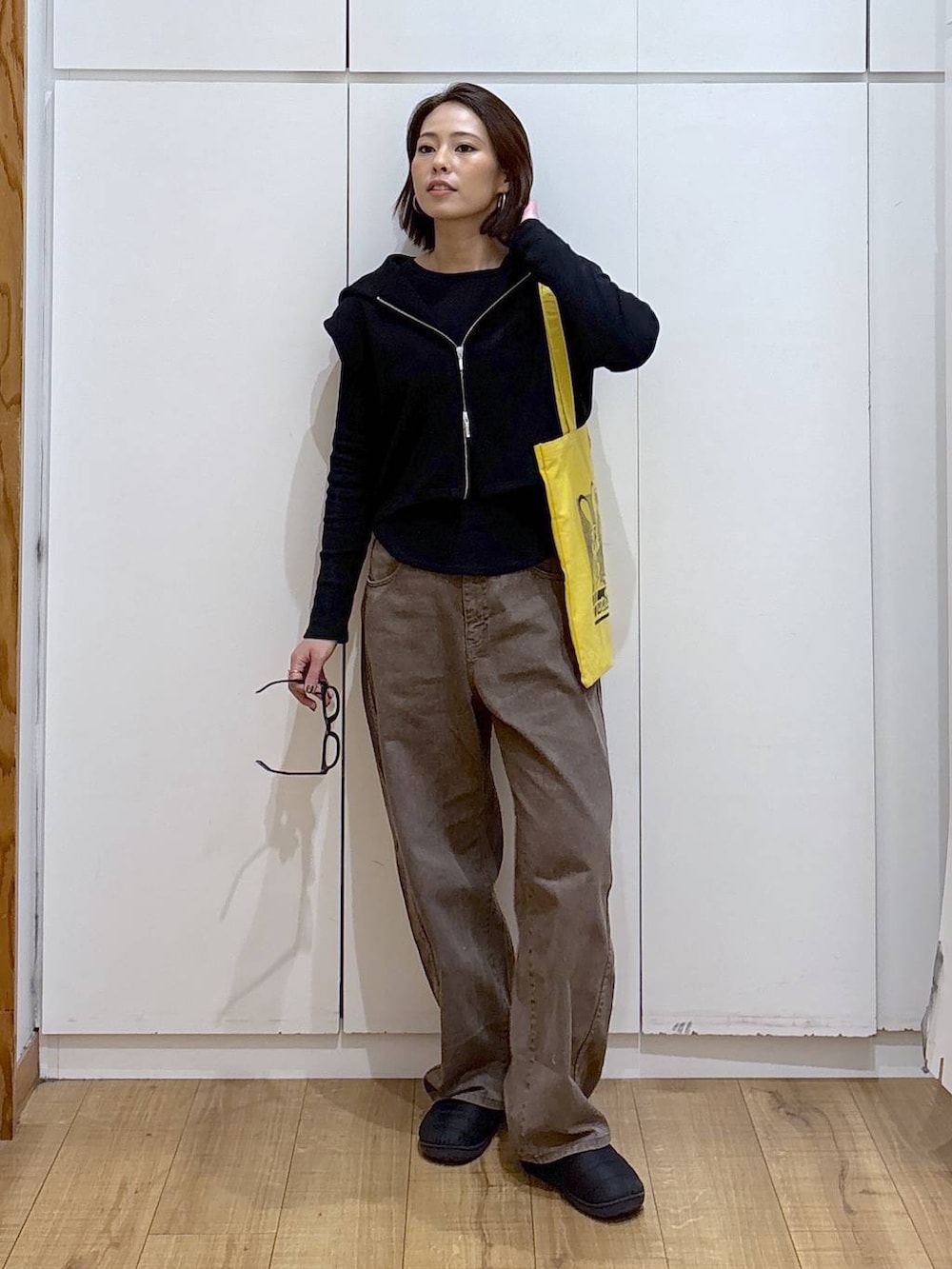 ブラウン系のデニムパンツ、イエロー系のトートバッグ、ブラック系のTシャツ/カットソーを着用したレディースの冬コーディネートの2枚目の写真