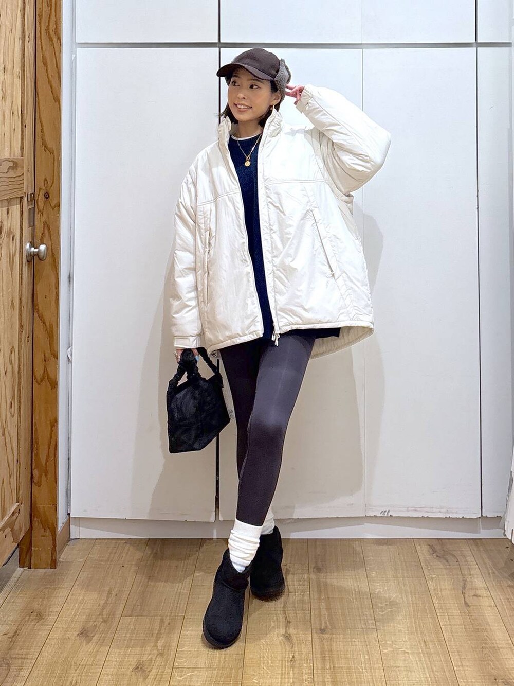 ブラック系のショルダーバッグ、ベージュ系のブルゾン、ホワイト系のTシャツ/カットソーを着用したレディースの冬コーディネートの2枚目の写真