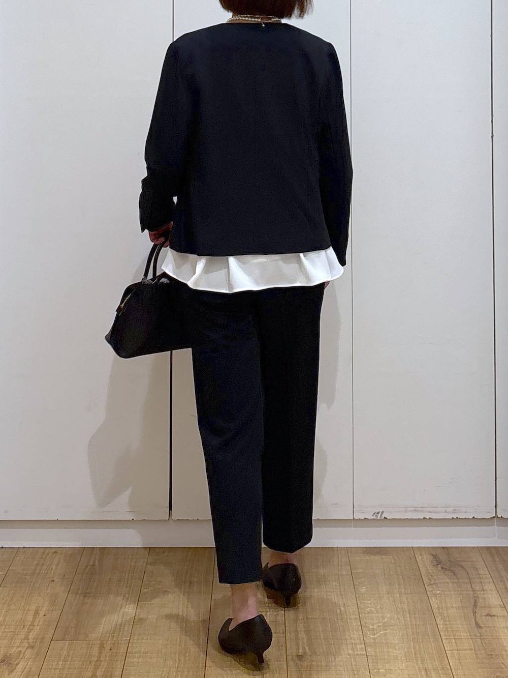 ブラック系のショルダーバッグ、ブラック系のパンプス、ブラック系のセットアップを着用したレディースの冬コーディネートの6枚目の写真