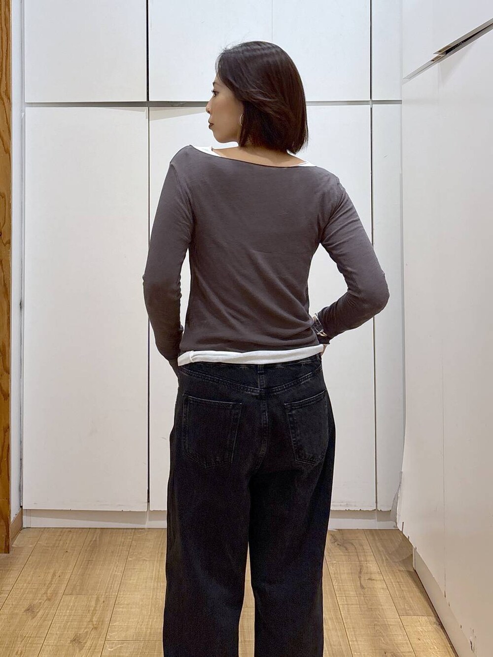 ブラック系のデニムパンツ、ブラック系のスニーカー、ホワイト系のTシャツ/カットソーを着用したレディースの秋コーディネートの6枚目の写真