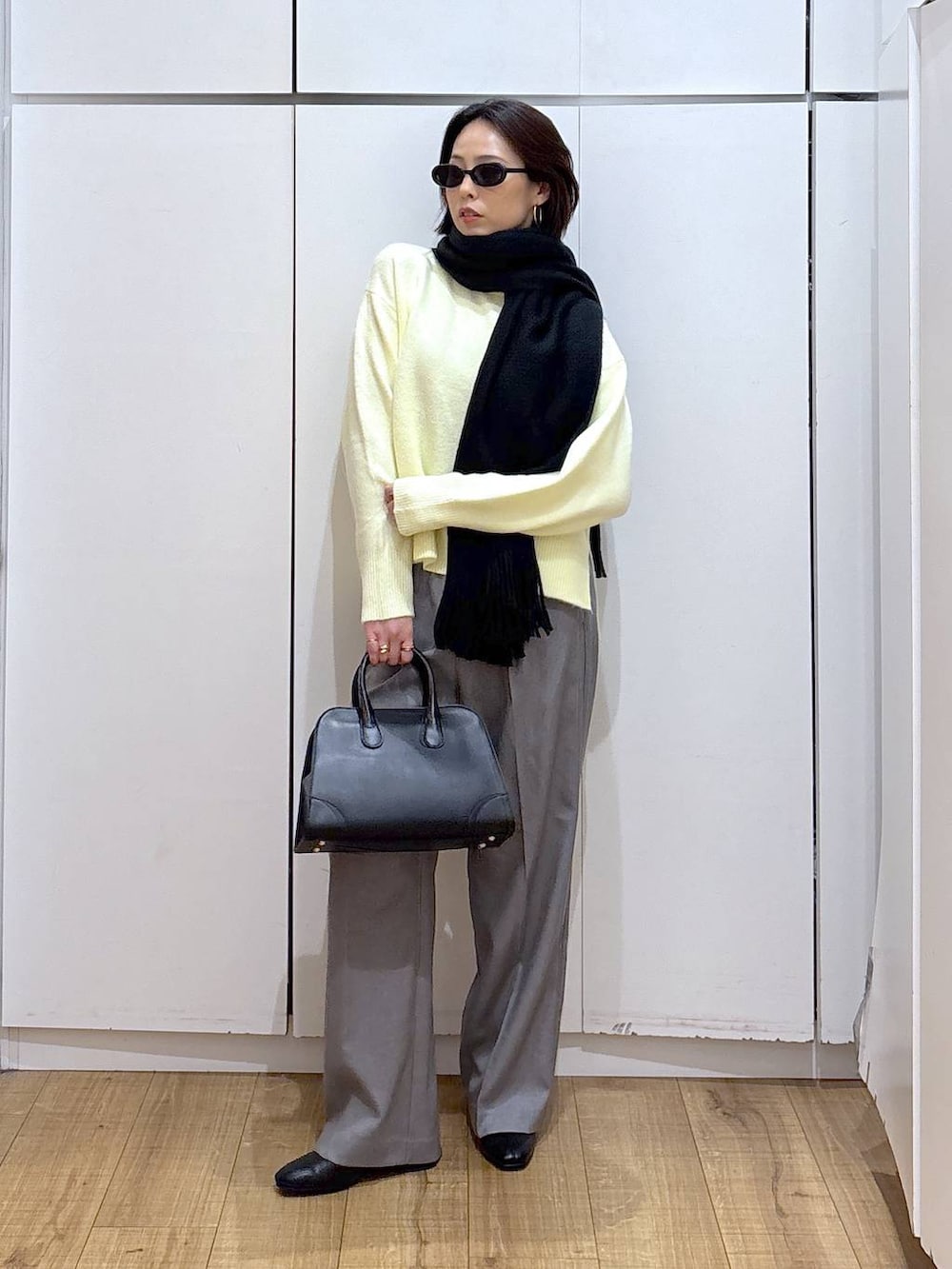 イエロー系のニット/セーター、グレー系のその他パンツ、ブラック系のショルダーバッグを着用したレディースの冬コーディネートの3枚目の写真
