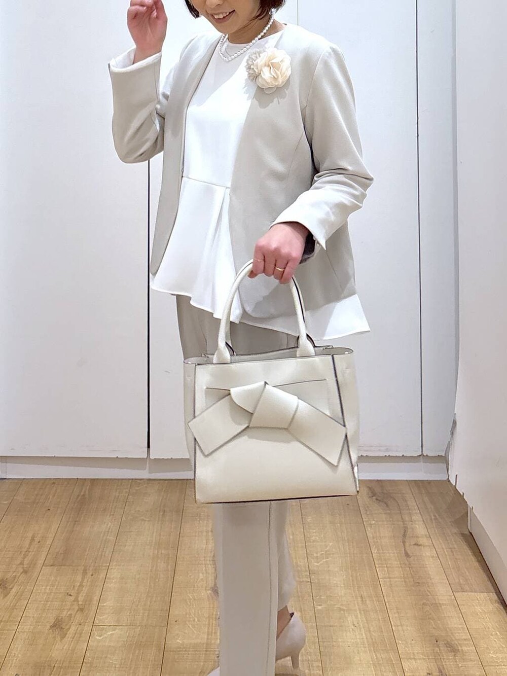 ホワイト系のパンプス、ベージュ系のセットアップ、ベージュ系のハンドバッグを着用したレディースの冬コーディネートの8枚目の写真