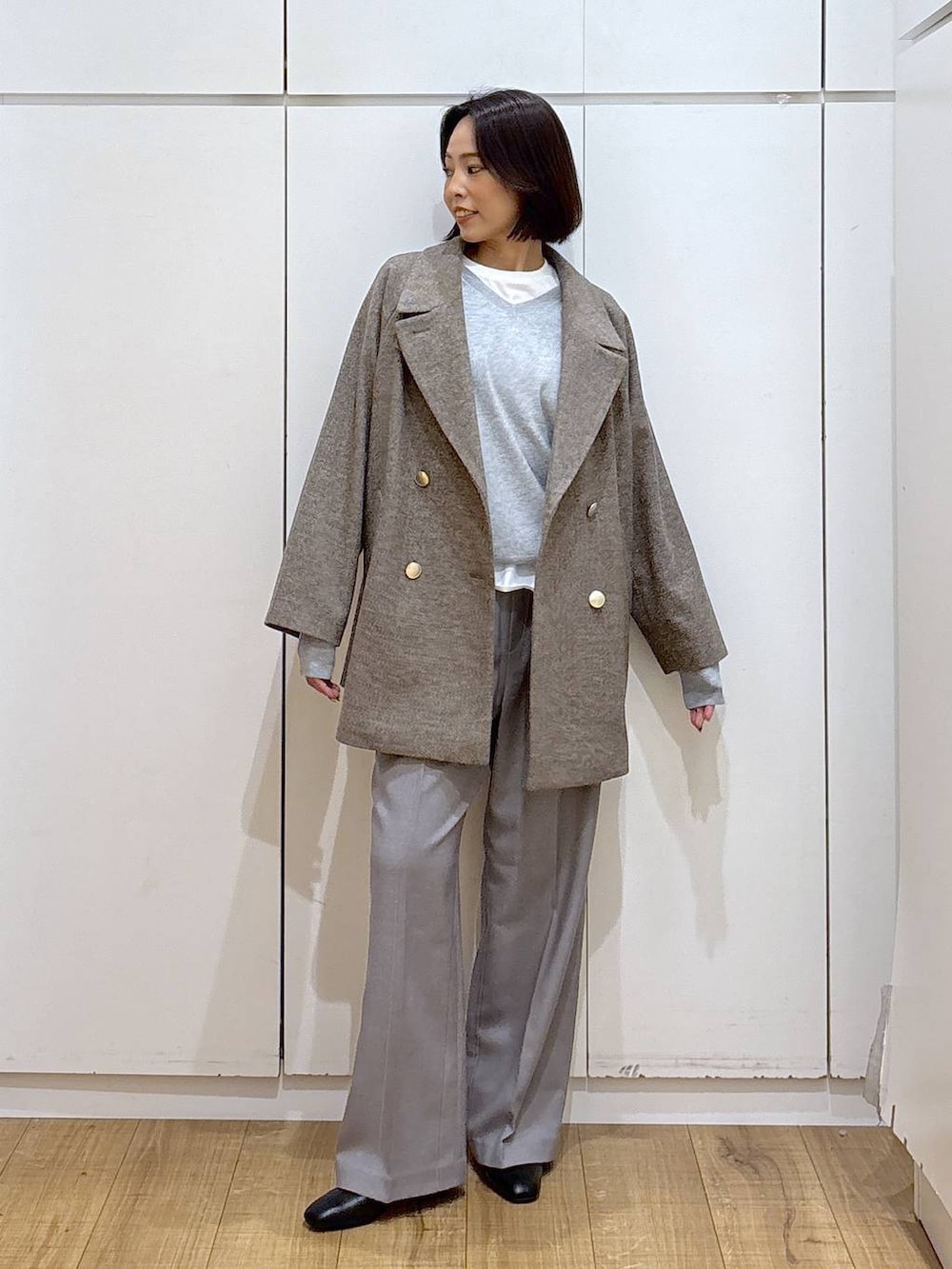 ブラウン系のチェスターコート、グレー系のその他パンツ、ホワイト系のTシャツ/カットソーを着用したレディースの秋コーディネートの2枚目の写真