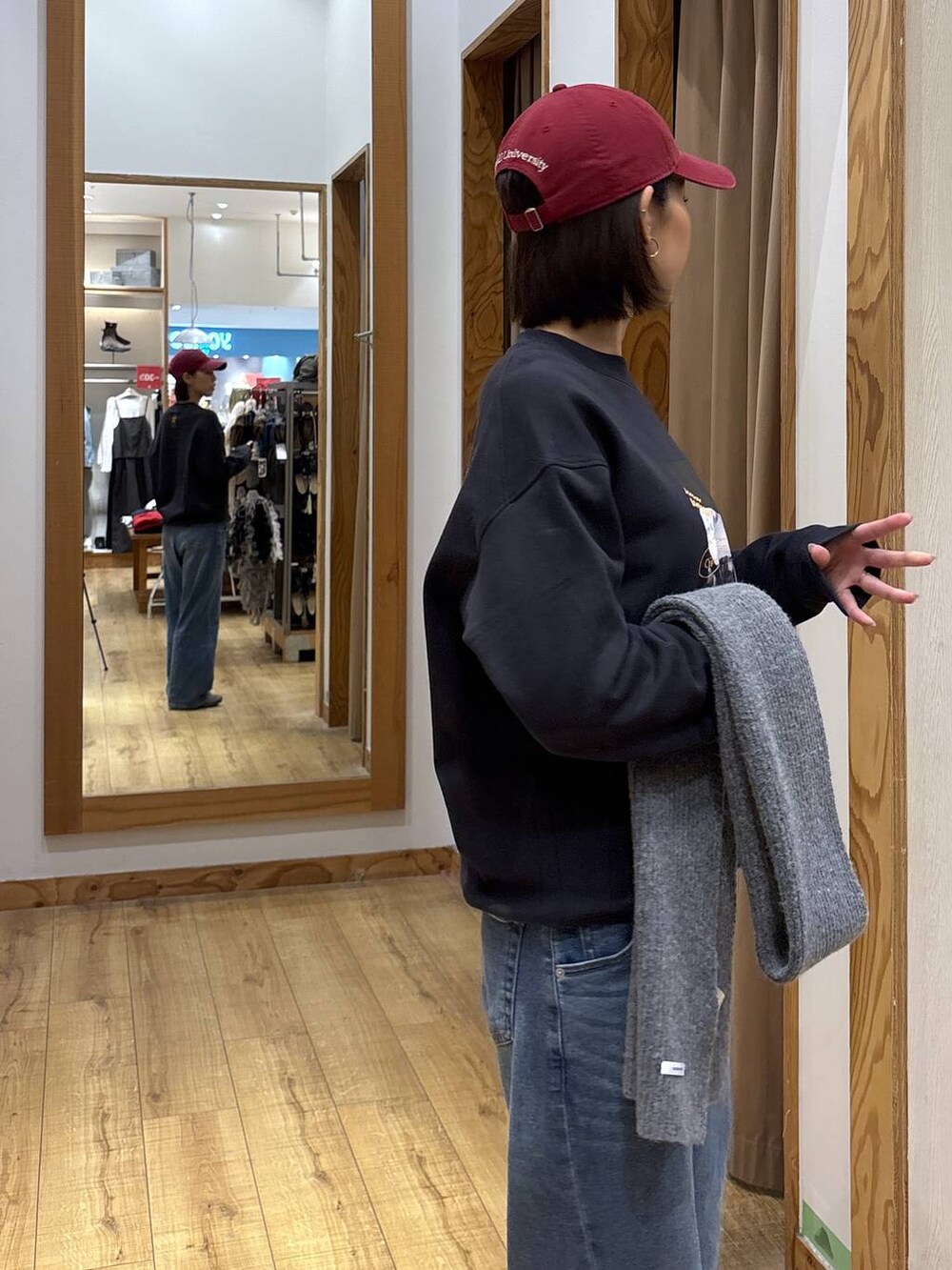 グレー系のスウェット、ブルー系のデニムパンツ、レッド系のハットを着用したレディースの秋コーディネートの8枚目の写真