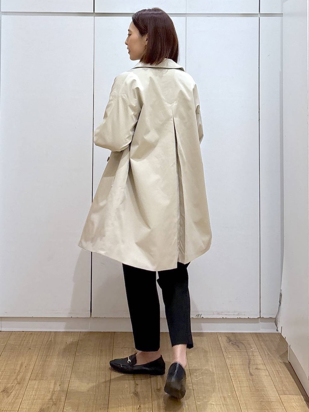 ブラック系のローファー、ブラック系のスラックス、ベージュ系のステンカラーコートを着用したレディースの春コーディネートの3枚目の写真