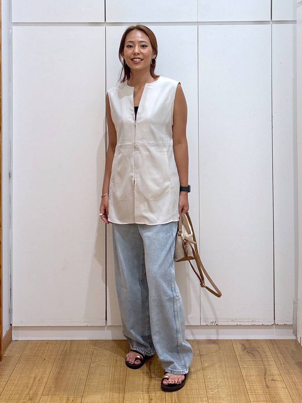 ブルー系のデニムパンツ、ホワイト系のショルダーバッグ、ブラック系のキャミソールを着用したレディースの夏コーディネートの7枚目の写真