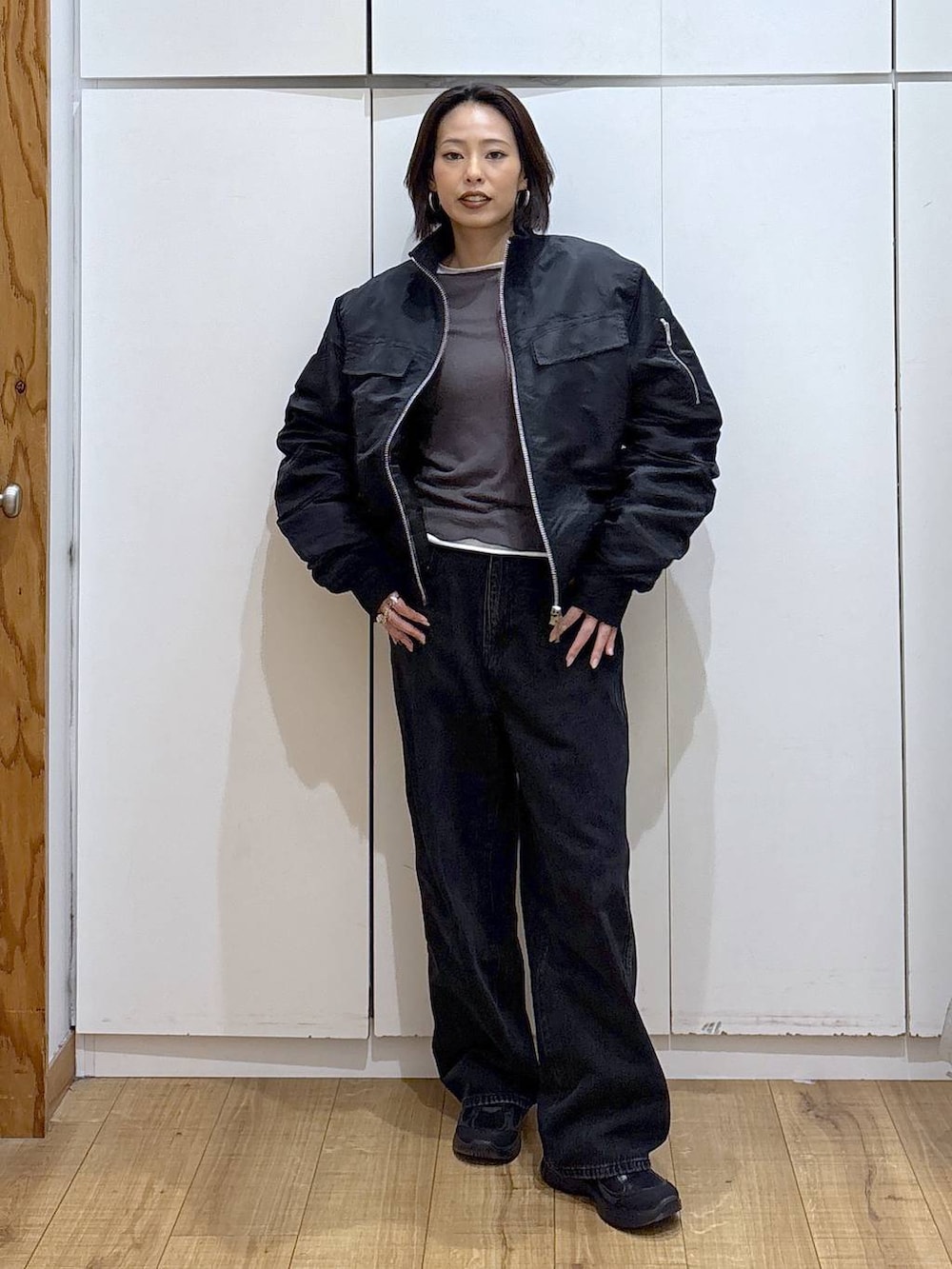 ブラック系のデニムパンツ、ブラック系のスニーカー、ホワイト系のTシャツ/カットソーを着用したレディースの秋コーディネートの2枚目の写真