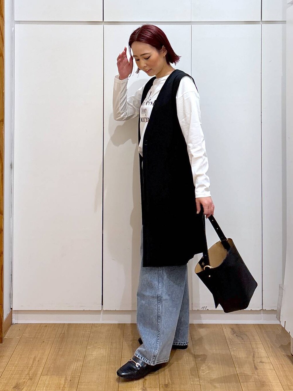 ブルー系のデニムパンツ、ブラック系のローファー、ブラック系のベストを着用したレディースの春コーディネートの3枚目の写真